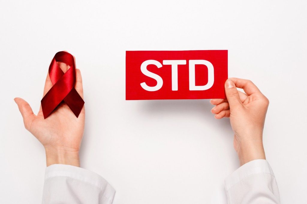 Hands holding a red awareness ribbon and an "STD" sign, promoting same day STD test in Shenandoah.