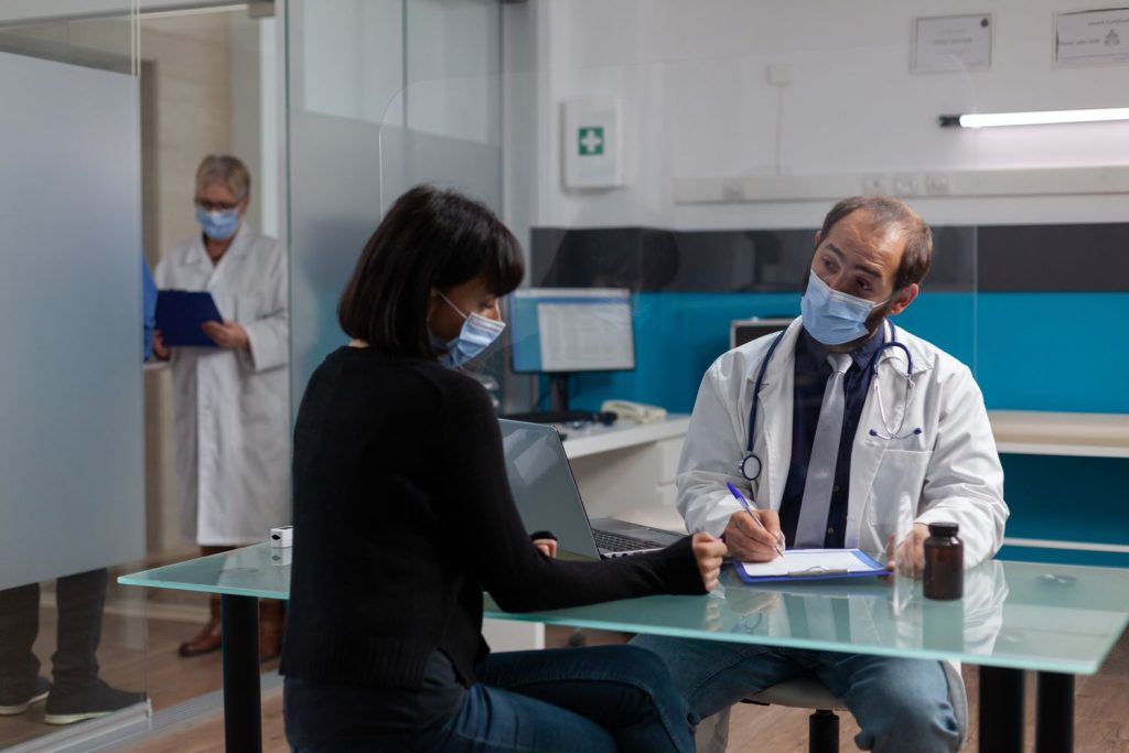 Same day STD test Houston: Doctor discussing with patient at desk, providing same-day STD testing in a professional setting.
