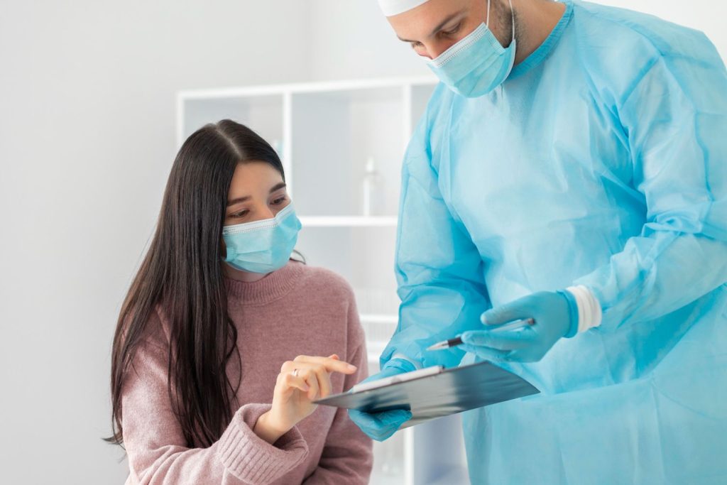Same day STD test Houston: Doctor in protective gear reviewing clipboard with masked patient in a clean clinic setting, ensuring rapid and confidential testing.