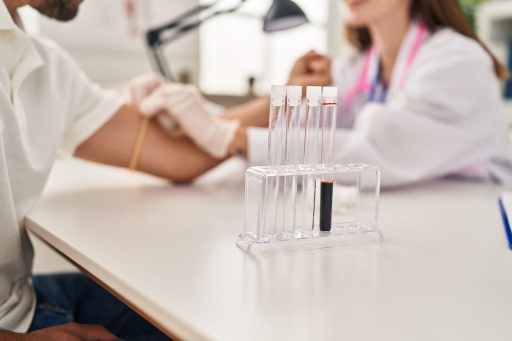 Same day STD test Houston: Lab technician drawing blood for quick STD analysis with vials on rack, providing efficient same-day results