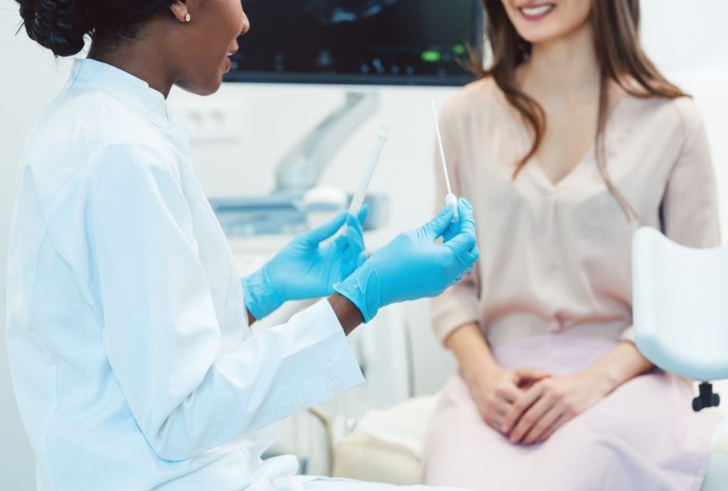 Doctor holding swab and test tube in clinic, explaining patient care and affordable std testing houston option