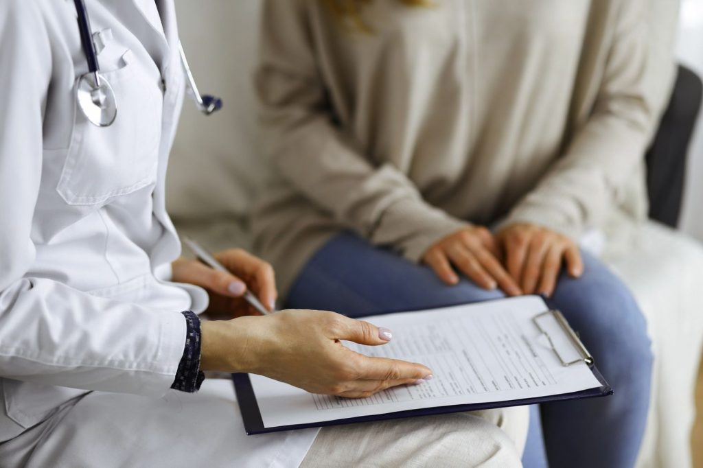 Doctor reviewing patient form on clipboard during consultation — same day std test houston, compassionate, confidential care