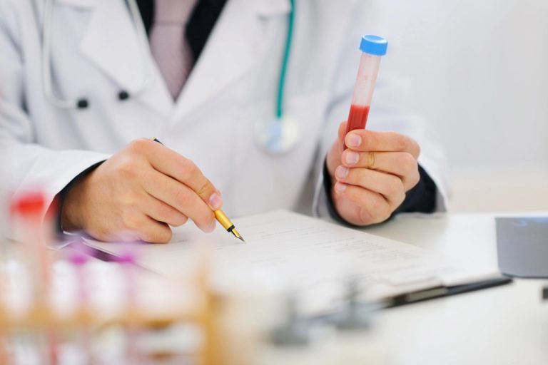 Doctor reviews paperwork while holding blood sample tube; trusted diagnostics and same-day care at best std testing houston.