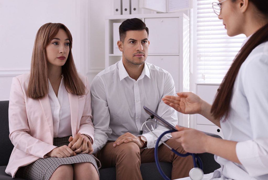 A concerned young couple receiving medical advice from a professional healthcare provider during an STD clinic visit.