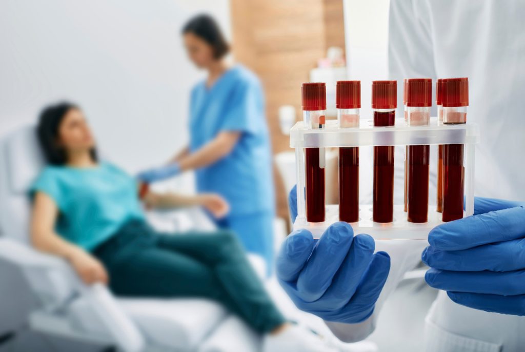 Gloved medical professional holding blood samples after a draw for confidential and cheap STD testing Houston.