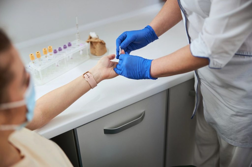 Professional clinician performing a rapid finger prick blood test for cheap std testing houston clinic services.
