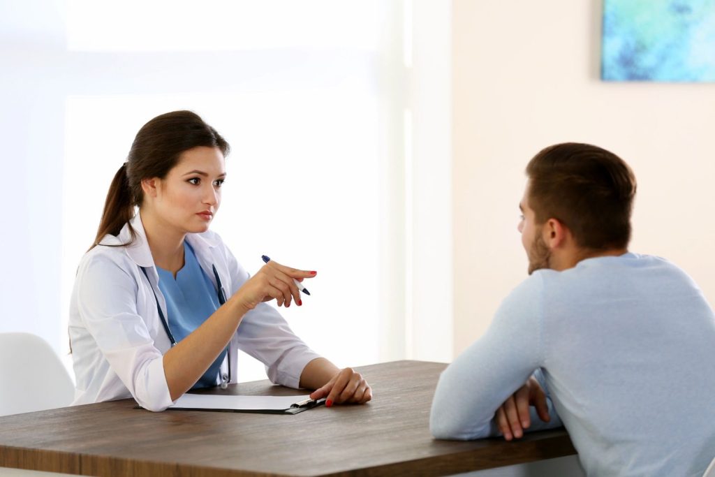 Professional female doctor discussing walk in std testing Houston options with a male patient in a bright medical office.