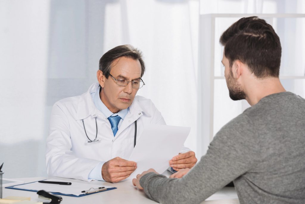 A male doctor in a white coat reading patient's medical history during walk in STD testing in Houston