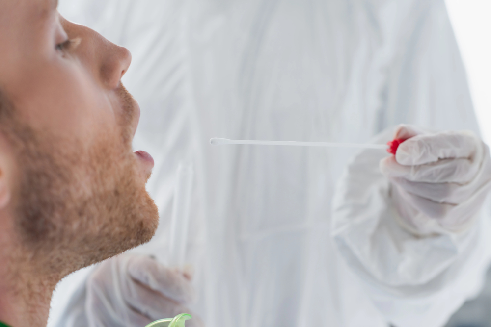 Mouth of patient being swabbed by medical staff in a protective suit for discreet Herpes testing Houston at a local clinic.
