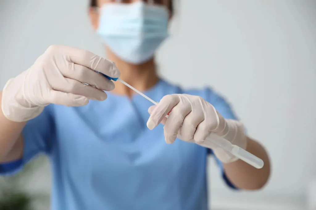 Close-up of medical personnel in blue scrubs and gloves, holding a sterile swab. Prepared for confidential std testing Houston.