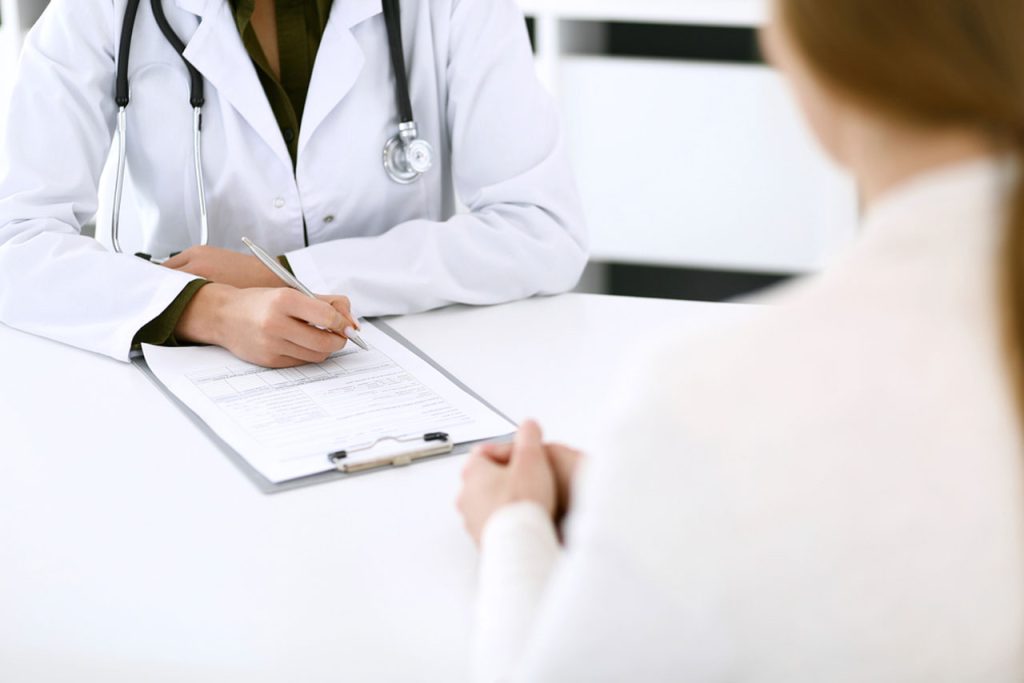 An experienced physician in a Houston clinic documents details on a form for a patient seeking a same day std test.